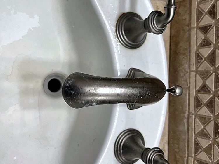 New brushed-nickel faucet and handles on a white bathroom sink