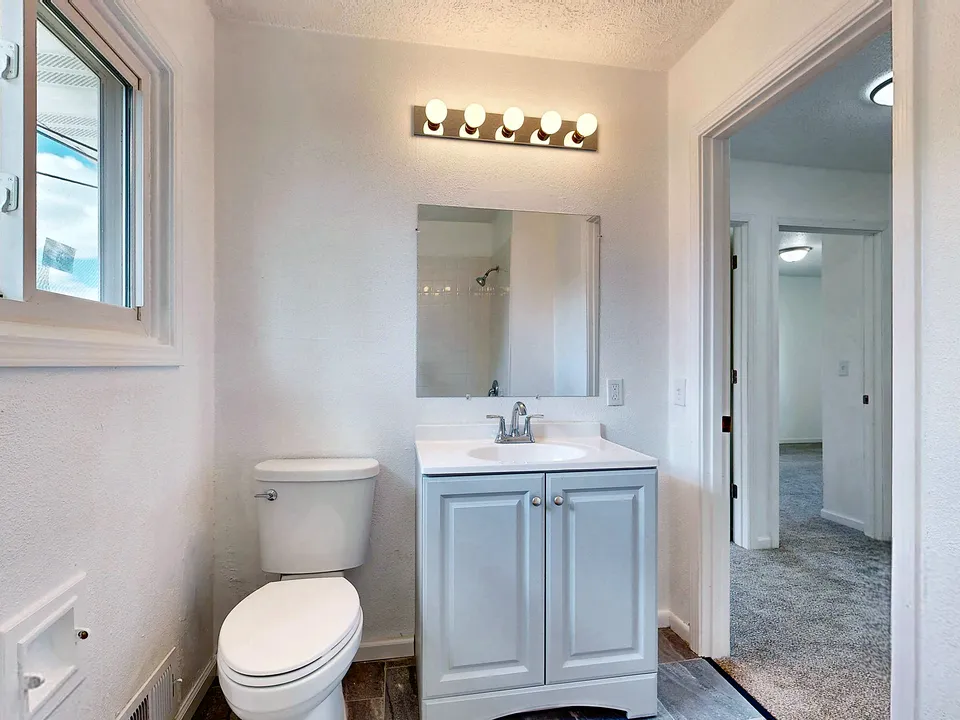 White bathroom with a vanity light and window