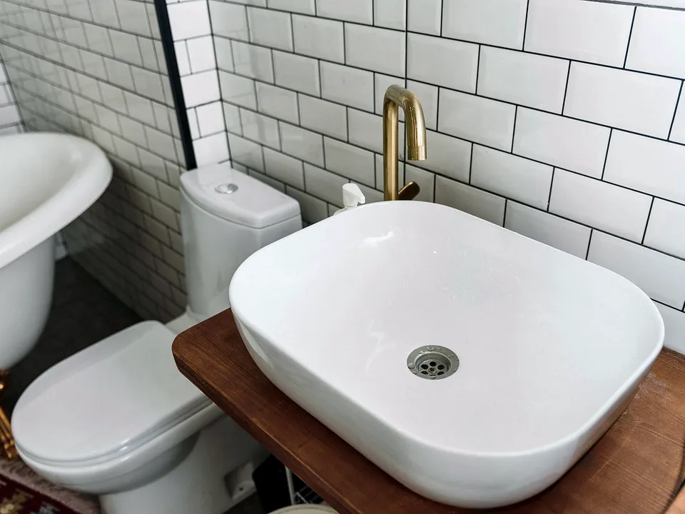 White vessel sink on a wood counter with subway tile