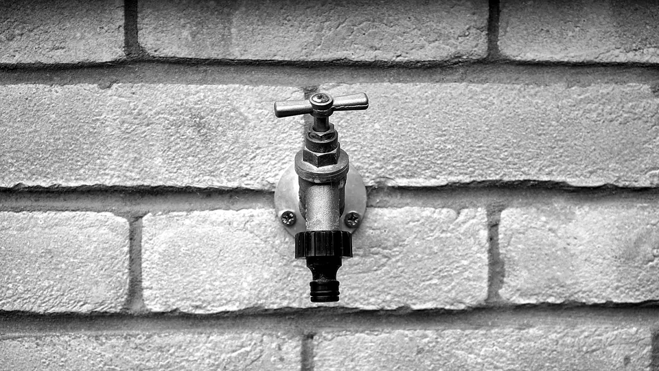 Outdoor spigot on a painted brick wall