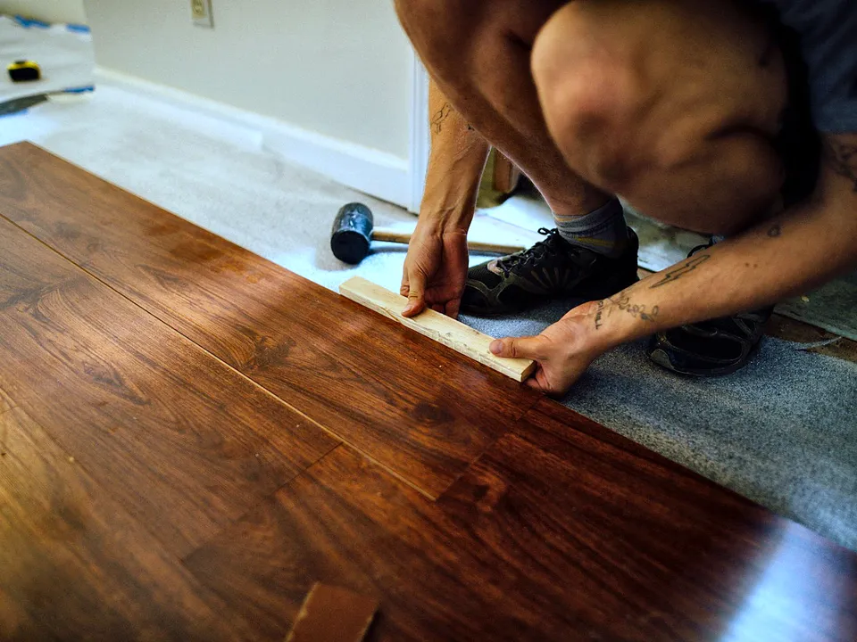 Installer fitting a plank into place on a floor