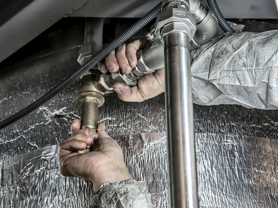 Hands tightening a fitting on a metal pipe