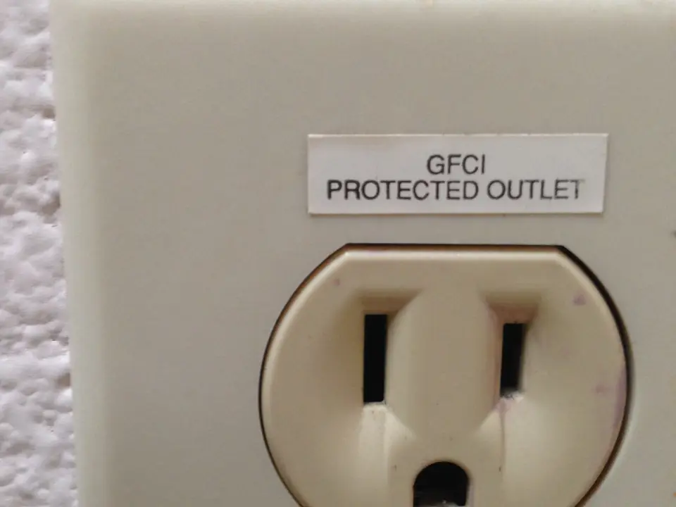 Ivory outlet cover with a label reading GFCI protected outlet above the receptacle