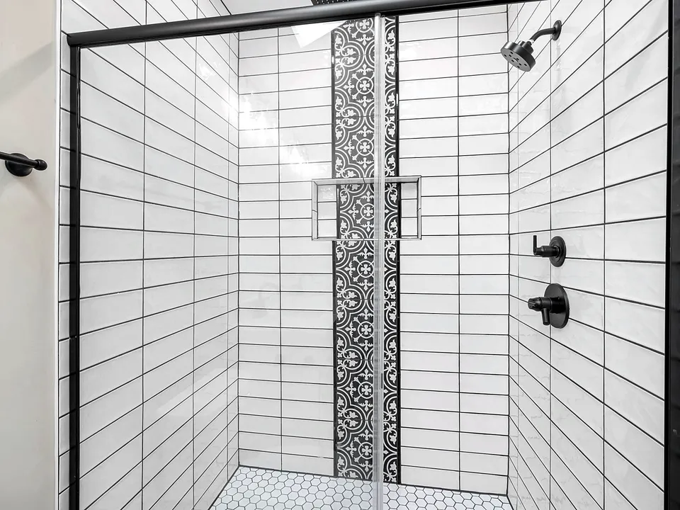 Shower with white tile and a patterned accent strip