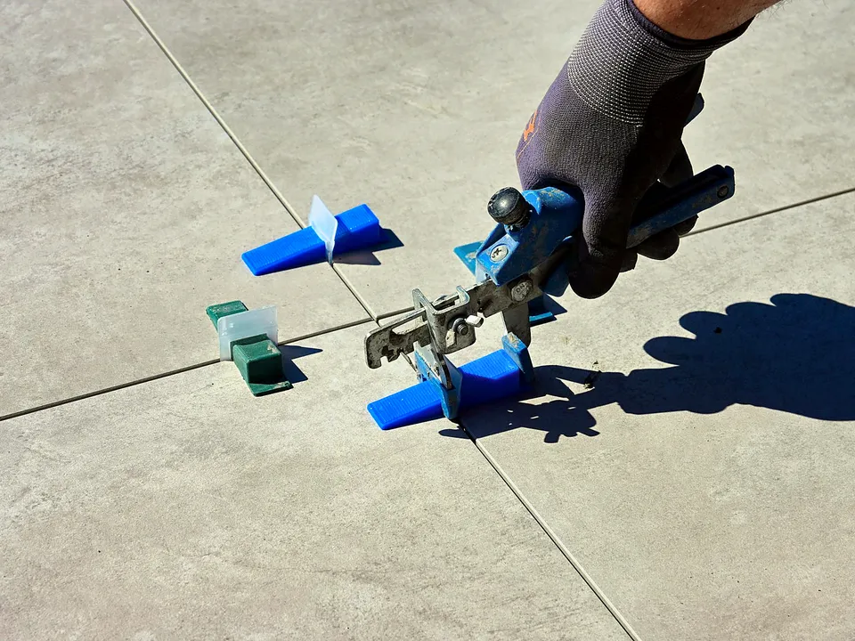 Gloved hand setting tile leveling clips on a floor