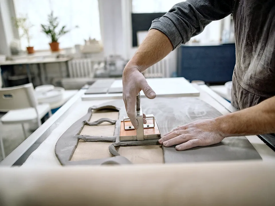 Hands scoring a tile on a manual tile cutter