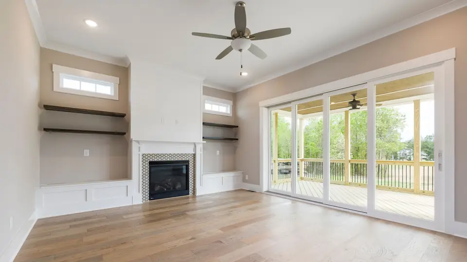 Empty living room with a ceiling fan, a fireplace and sliding glass doors to a covered patio