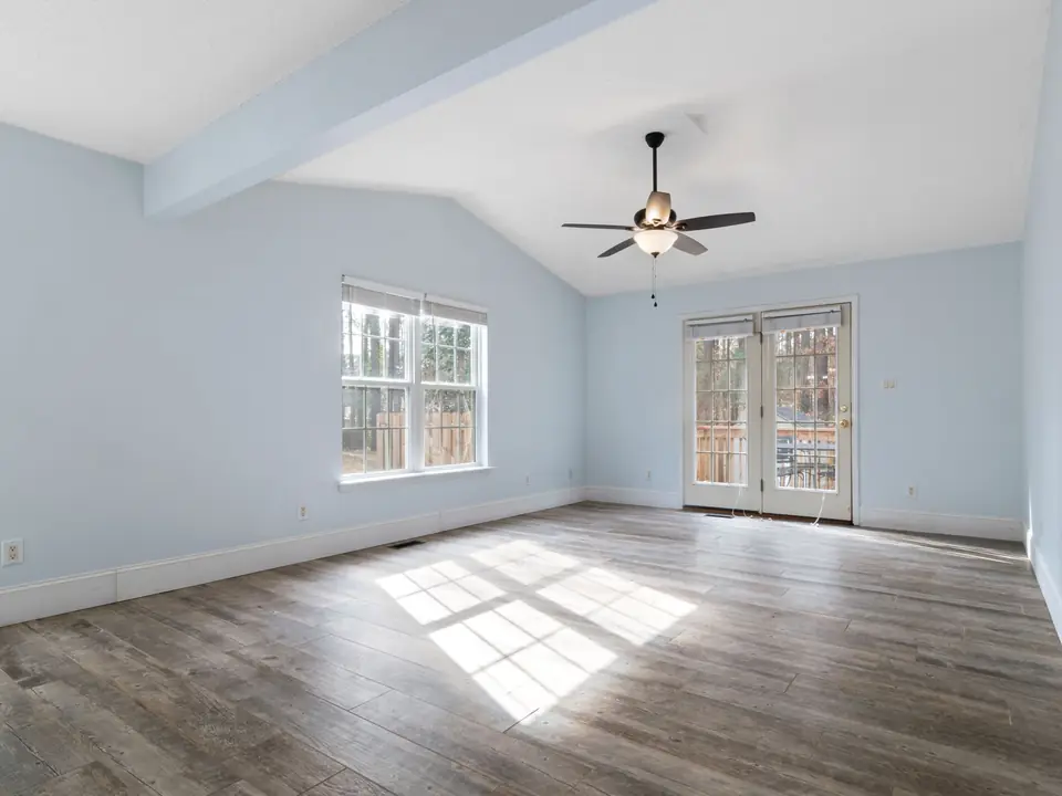 Ceiling fan hanging from a downrod under a sloped ceiling with a painted beam