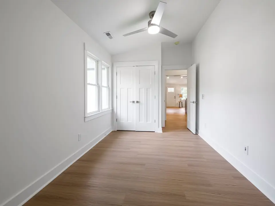 White three-blade ceiling fan with a round LED light in an empty bedroom
