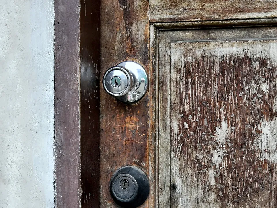 Door knob and deadbolt on a weathered wood door