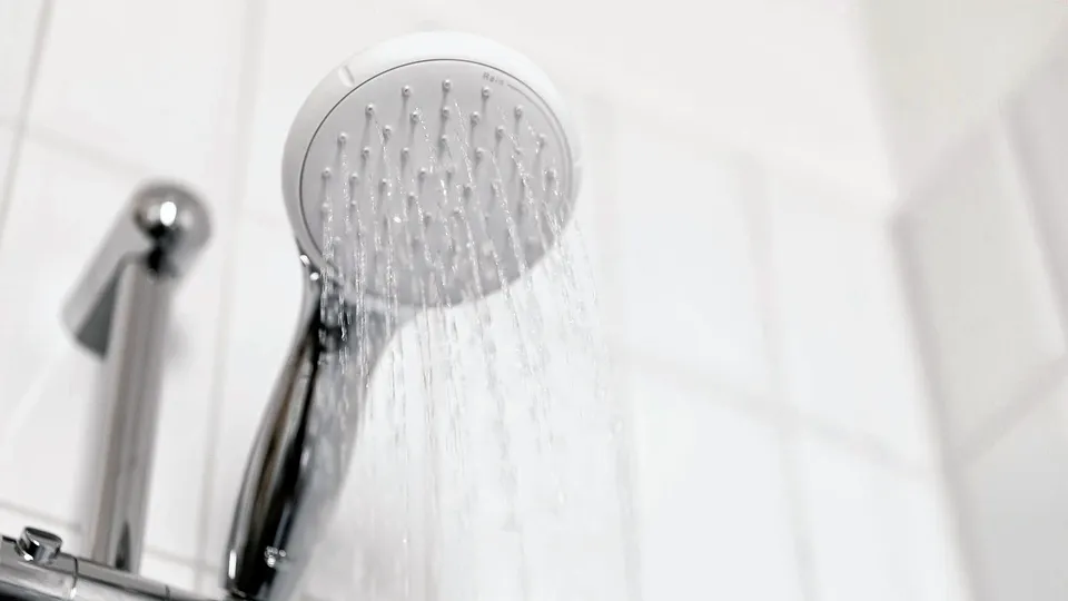 Handheld shower head on a chrome slide bar against white tile