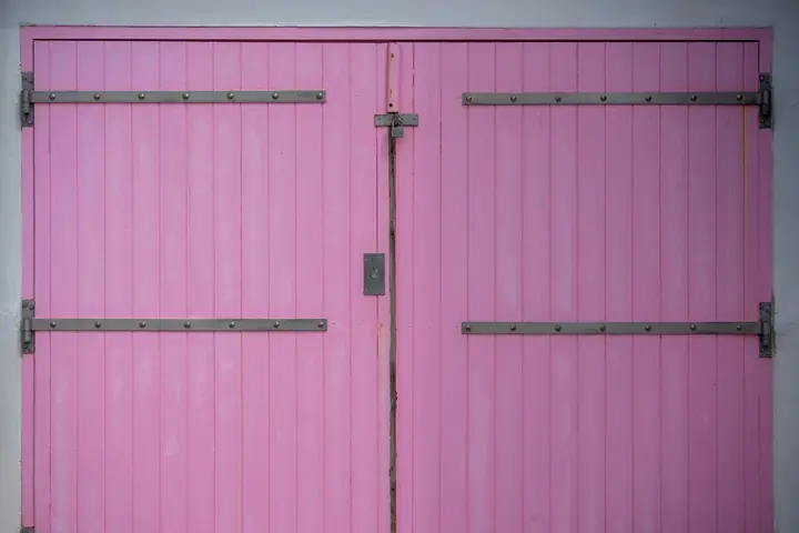 Bright pink wooden double door with metal hinges