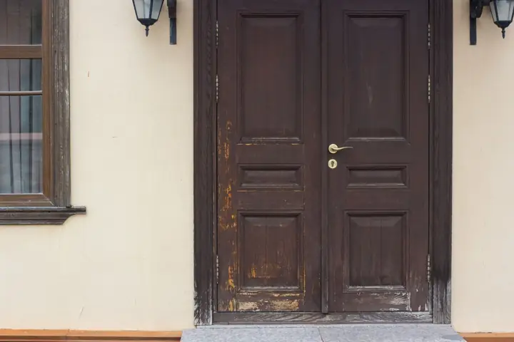 A rustic wooden double door entrance with vintage lanterns, showcasing traditional architectural style