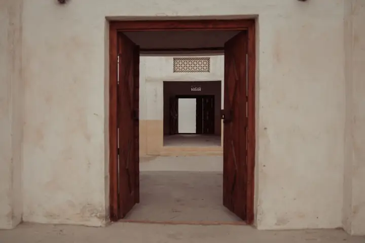 Rustic wood doors open into a historical building corridor, showcasing architectural charm