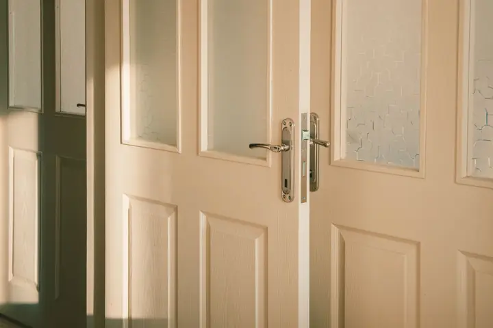 Wooden doors with frosted glass panels softly illuminated by streaming sunlight