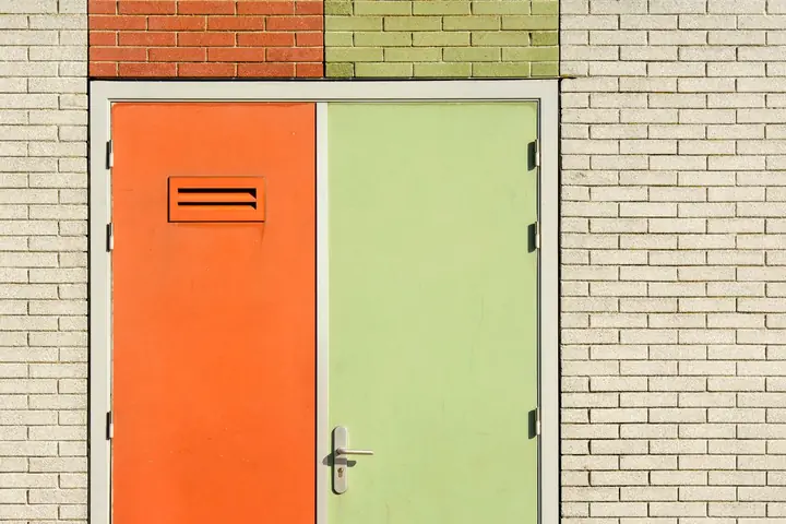 Orange and green door on a brick wall with modern design and security features