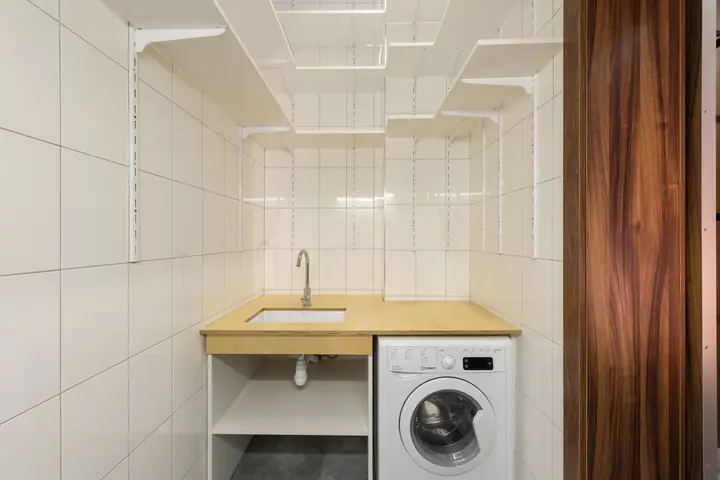 Clean and minimalist laundry room with washing machine and open shelving
