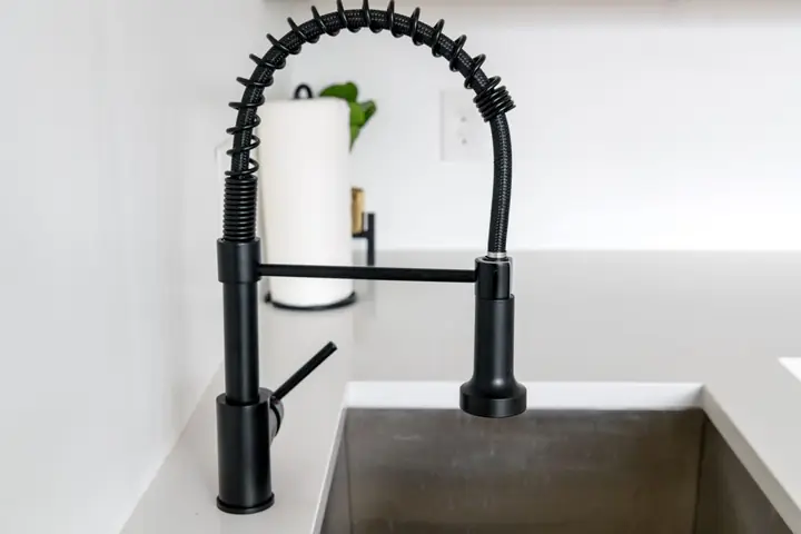 Black faucet on white countertop in modern kitchen
