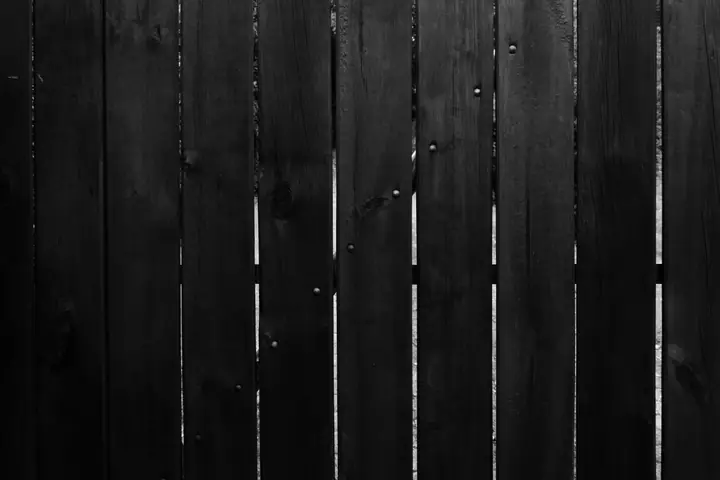 Black and white photo of vertical wooden fence panels with natural textures and details