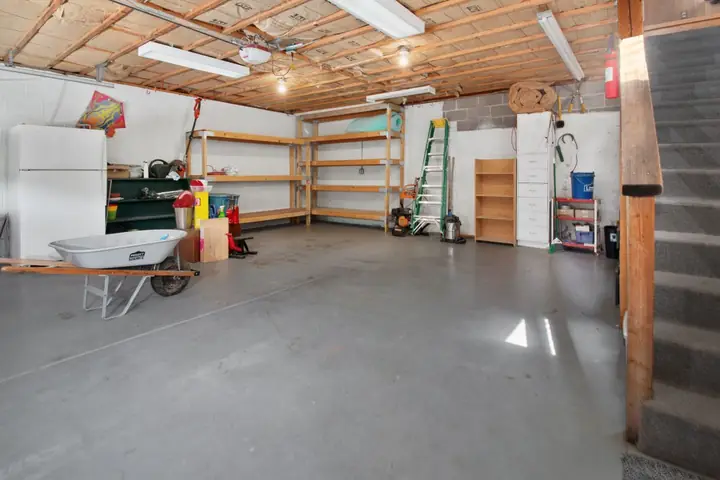 Garage interior with storage shelves, tools, and a wheelbarrow