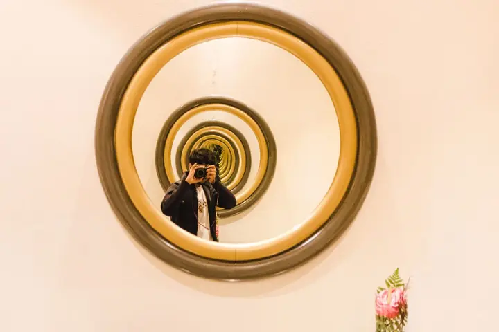 A photographer taking a picture through multiple mirrors creating a visual infinity effect indoors