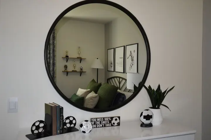 A bedroom with soccer-themed decorations reflected in a round mirror