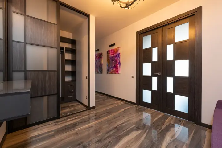 Contemporary room interior with closet on floor reflecting door against paintings on wall in light house