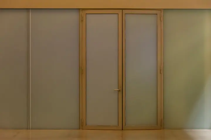 A minimalist beige door with frosted glass panels creating a modern aesthetic in an indoor setting