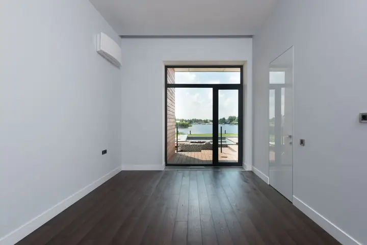 Perspective view of empty hallway with white walls and large window overlooking lake in modern suburban cottage house