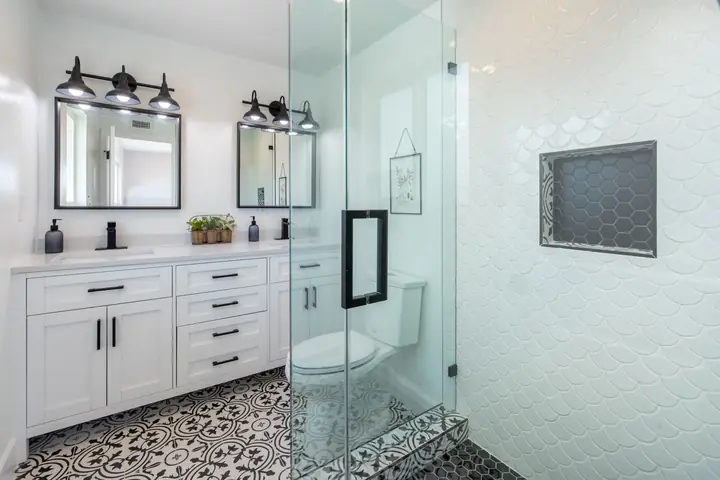 White bathroom with glass shower and patterned floor