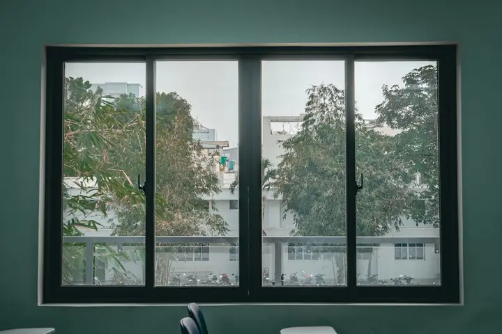 Serene view through a large window of an urban classroom, featuring trees and cityscape