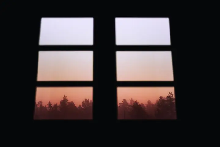 Sunrise through a window, overlooking a misty forest