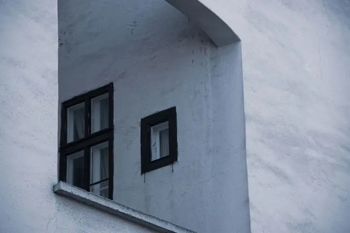 A close-up of a building facade with black-framed windows and concrete texture